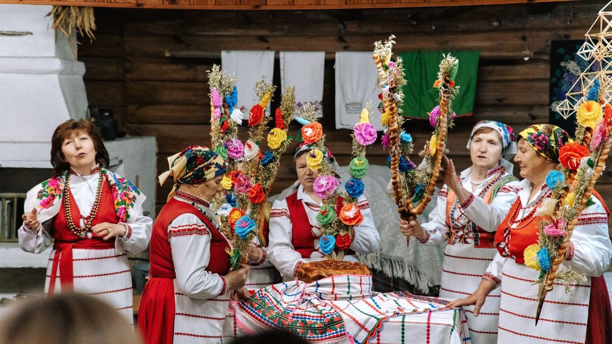 Five women in traditional attire holding vibrant decorations in a cultural celebration.